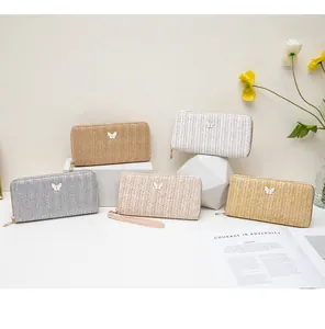 Cartera larga de textura paja con dijes de mariposa en cinco opciones de color