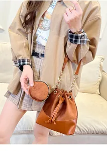 Detail of caramel suede bucket bag with gold chain strap and mini coin purse