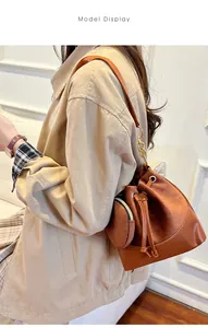 Brown bucket bag with drawstring and matching coin purse on model in a warm home setting