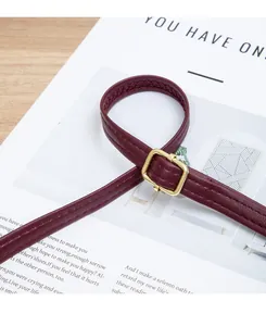Close-up of deep red leather shoulder strap with golden square buckle and fine stitching