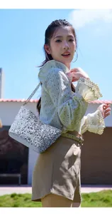 Close-up of silver sequin bucket bag with gold chain strap against a blue sky