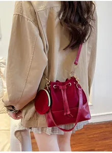 Detail of burgundy bucket bag with suede拼接 and matching mini round coin purse pendant