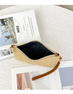 Dettaglio della pochette in paglia intrecciata con cerniera dorata e cinturino marrone