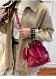 Detail of burgundy velvet and leather bucket bag with drawstring and mini pouch