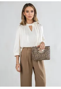 Borsa leopardata con manico dorato abbinata a camicia di seta e pantaloni kaki di classe