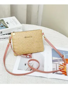 Dettaglio borsa a tracolla in paglia intrecciata con tracolla in pelle rosa e metallo oro