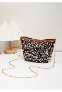 Detailed close-up of a black sequin bucket bag with gold chain strap and brown leather trim