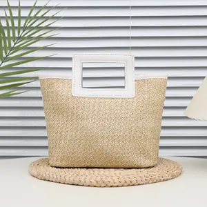 Woven straw handbag in natural wood color with white leather handles and trim accents