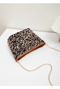 Detailed view of gold sequins on crossbody bag with brown leather trim and chain strap