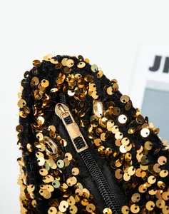 Close-up of smooth gold metal zipper and shimmering sequins on a black shoulder bag