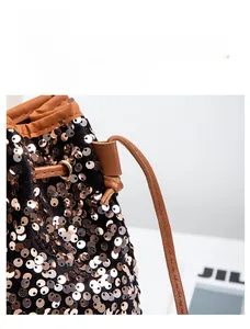 Vue macro d'un sac seau à paillettes dorées, bandoulière en cuir et cordon de serrage