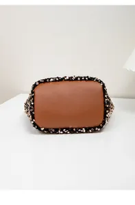 Detailed macro view of the caramel brown leather bucket bag base with golden sequins