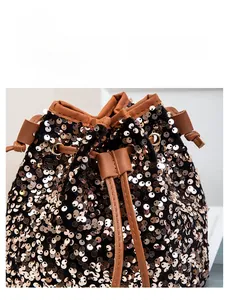 Détail des paillettes dorées et du cordon en cuir marron sur un sac seau élégant