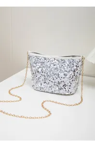 Macro shot of silver sequins on small bucket bag with golden chain strap detail