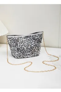 Close-up of sparkling silver sequins and gold chain strap on the bucket bag