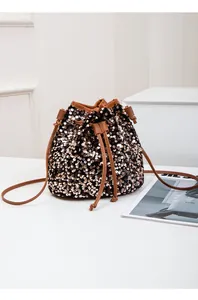 Détail du sac seau à paillettes avec fermeture à cordon et bandoulière en cuir