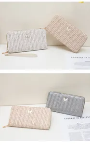 Detalle de carteras largas tejidas en blanco y beige con dijes de mariposa de metal fino
