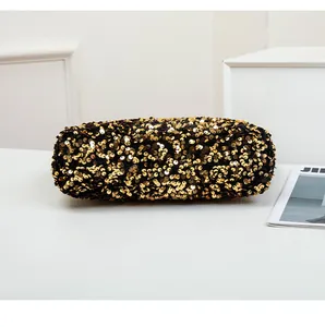 Macro shot of gold sequin cylinder clutch bag with shimmering metallic texture and luxury finish