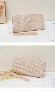 Detalle de cartera de paja tejida con hebilla de mariposa blanca y cremallera dorada