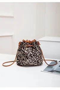 Détail du sac seau à paillettes noir-or avec bordure en cuir et cordon de serrage