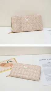 Detalle de billetera larga de paja con mariposa blanca y cremallera dorada