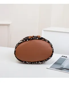 Détail d'un sac seau marron avec paillettes dorées et cordon de serrage sur fond blanc