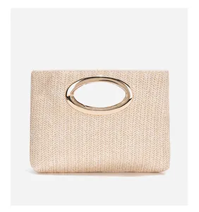 Dettaglio della borsa a mano in paglia intrecciata con elegante manico in metallo dorato