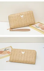 Detalle de cartera larga de paja tejida con adorno de mariposa y correa de mano