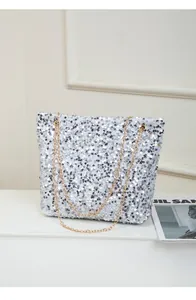 Close-up of shimmering silver sequins and elegant gold chain strap on shoulder bag