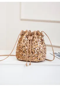 Détail d'un sac seau doré à paillettes avec fermeture à cordon et fine bandoulière