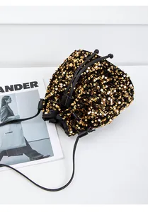 Détail de paillettes dorées sur un sac seau noir avec cordon et bandoulière en cuir