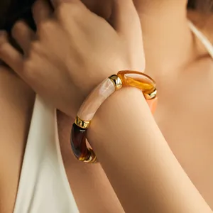 Nahaufnahme eines Bohemian-Harzarmbands mit Marmortextur und goldenen Metallakzenten