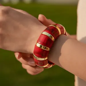 Close-up of bohemian stretch bracelet with red marble texture and gold metal ring connectors