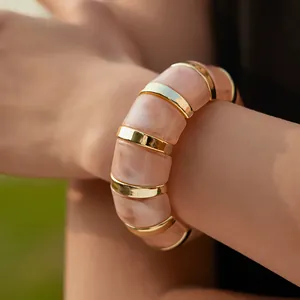 Close-up of pink marble resin blocks and gold metal spacers on a stretch bracelet