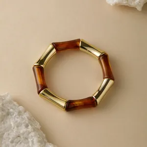 Dettaglio in resina tartarugata e segmenti dorati su un bracciale rigido geometrico