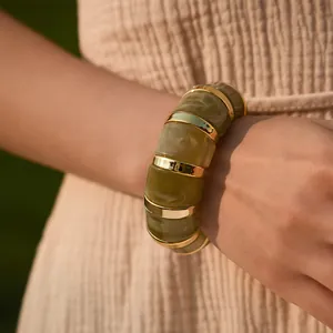 Detail of bohemian resin cuff bracelet with olive green marble texture and gold metal rings