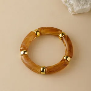 Nahaufnahme der Bernstein-Acrylperlen und goldenen Metall-Spacer auf dem elastischen Armband