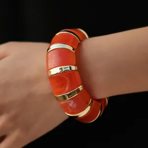 Macro detail of Bohemian orange marble resin bracelet with golden metal spacers and texture