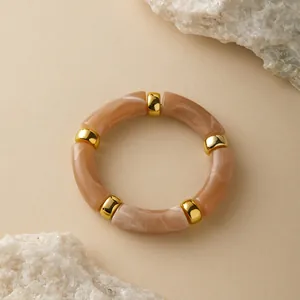 Detail eines böhmischen Acryl-Marmor-Harz-Armbands mit Goldperlen auf Steinhintergrund