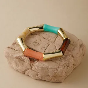 Dettaglio del bracciale a bambù in acrilico con trama marmorea e giunti in metallo dorato