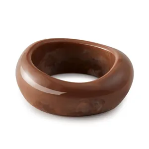 Macro detail of thick acrylic bangle featuring a brown marble texture and glossy finish