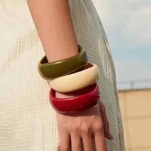 Bohemian acrylic resin bangles in green, cream, and burgundy on model's wrist