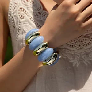 Detail of blue marble resin and gold metal bead bracelet worn on a model's wrist