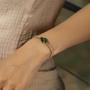 Detail of 18K gold plated bracelet featuring green square crystals and zircon inlay