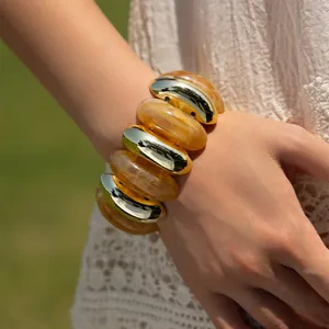 Detailed view of elastic bangle with golden metal and amber marble resin beads on wrist