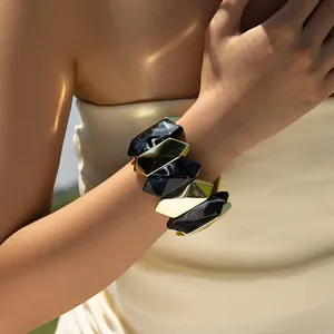 Detail of chunky black marble resin and gold metal geometric elastic bracelet on wrist