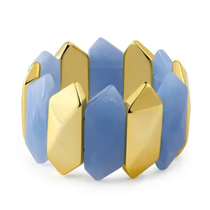 Macro view of geometric gold metal prisms and light blue resin textures on an elastic bracelet