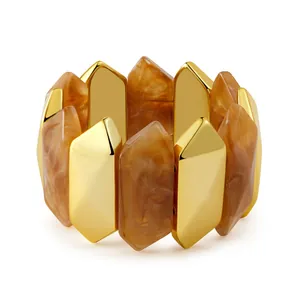 Primer plano de metal dorado y prismas de resina en esta pulsera elástica ancha