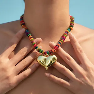 Détail d'un collier ras du cou perlé fait main avec pendentif cœur doré et perles rondes