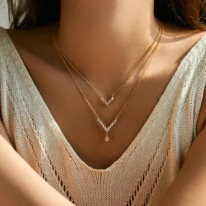 Close-up of double-layered gold V-shaped necklace with zircons and teardrop gemstone